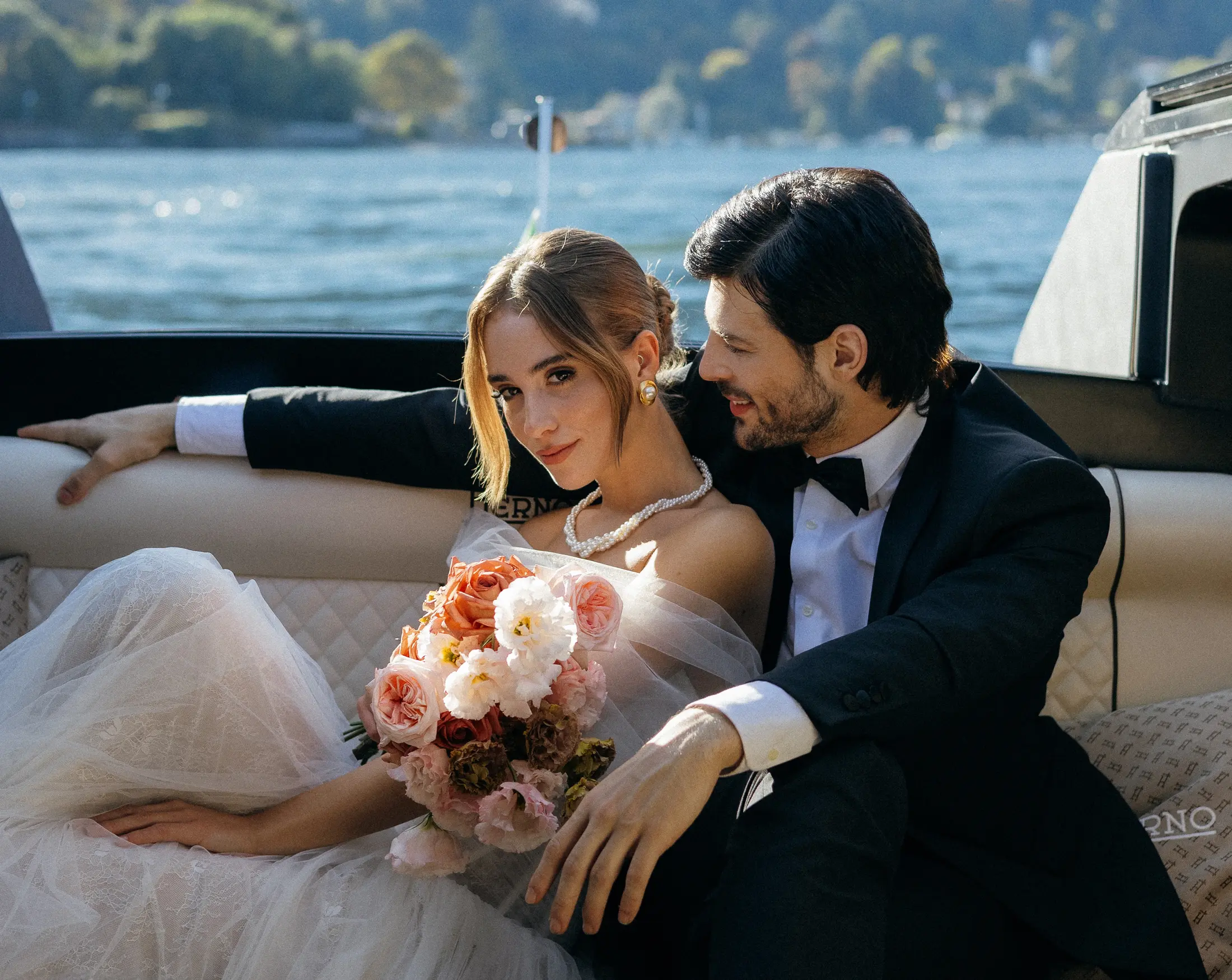 The newlyweds aboard the Aurum boat during a wedding photoshoot on Lake Maggiore, sitting together in an elegant and romantic atmosphere overlooking the water.